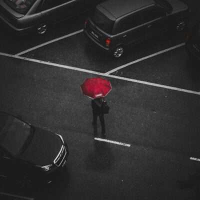 person holding red umbrella walking on street