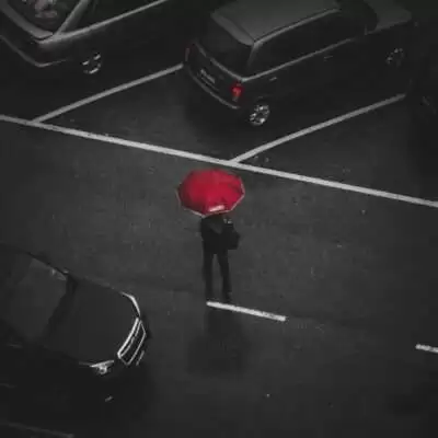 person holding red umbrella walking on street