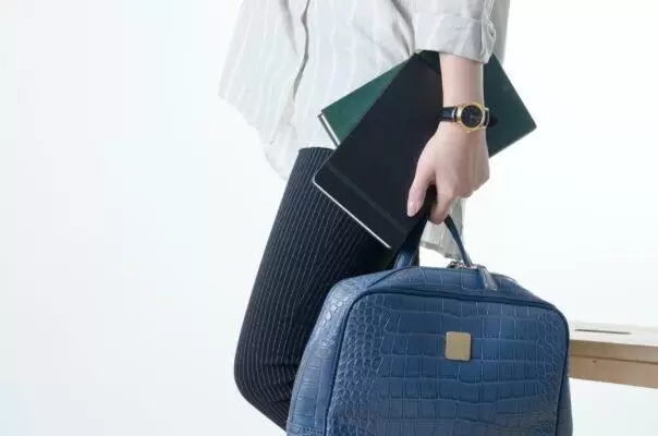 hand with notebooks and blue hand bag